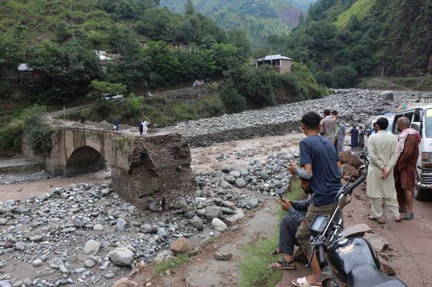 Residents gather at the site of a damaged bridge following a storm that caused heavy rains and flooding on the outskirts of Muzaffarabad