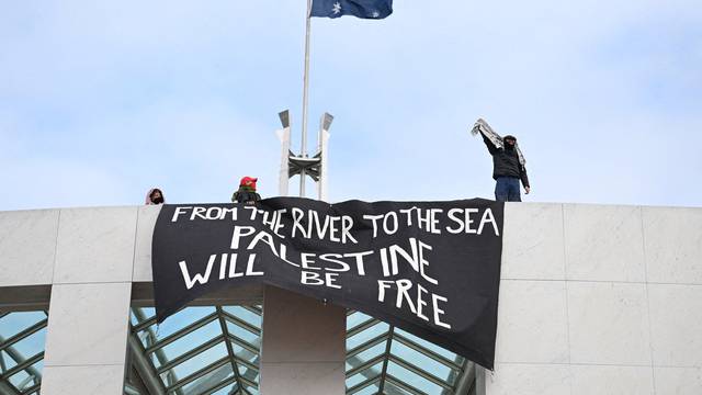 Pro-Palestinian protesters hang banners from the top of Parliament House in Canberra