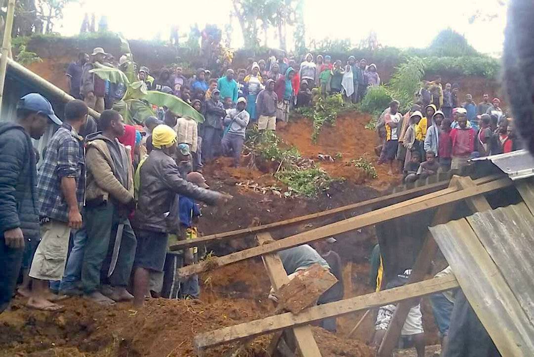 Locals surround a house that was covered by a landslide in the town of Mendi after an earthquake struck Papua New Guinea's Southern Highlands, in this image taken obtained from social media