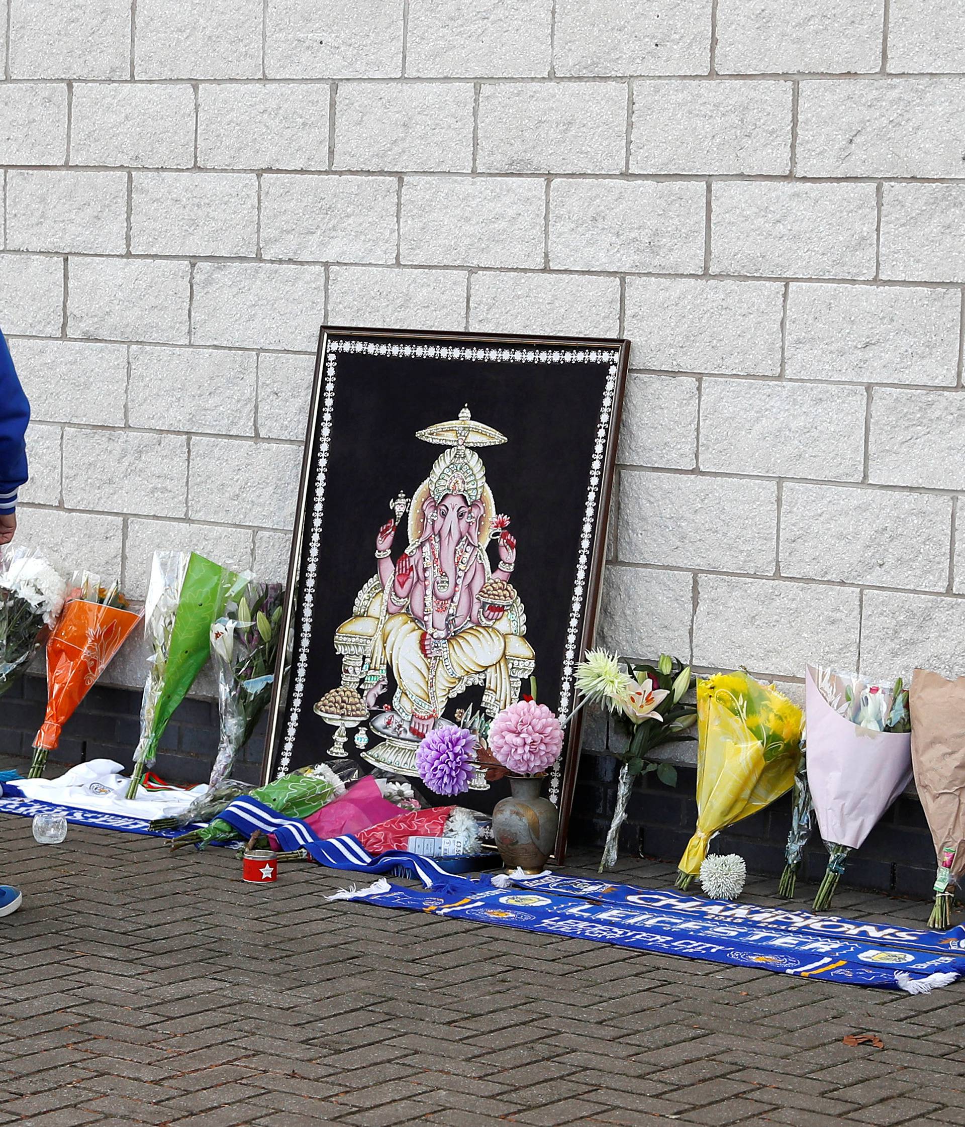 A Leicester City football fan places flowers outside the football stadium after the helicopter of the club owner Thai businessman Vichai Srivaddhanaprabha crashed when leaving the ground on Saturday evening after the match, in Leicester