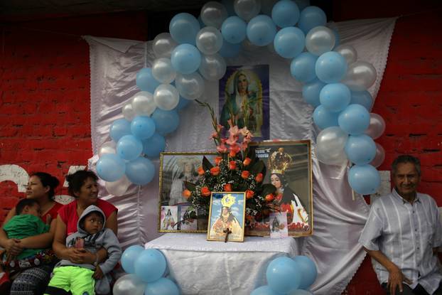A family gather next to religious icons outside their house, prior to Pope Francis