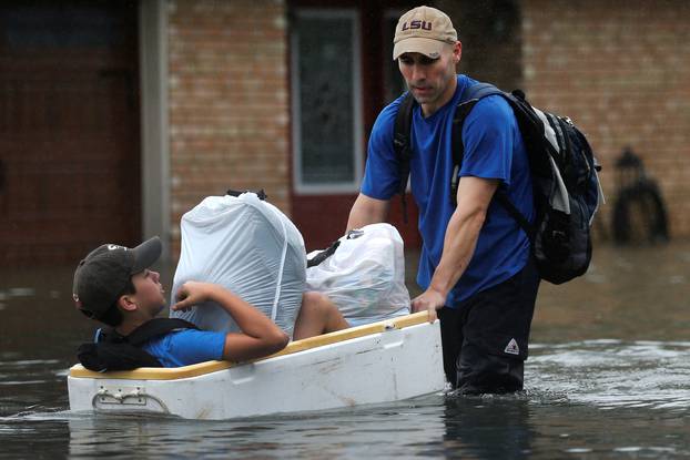 Tim Linscomb carries his 12-year-old son Colby as he wades through flood waters from Tropical Storm Harvey in Orange