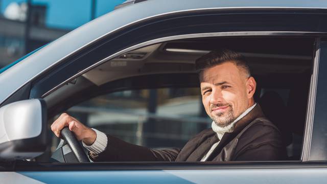 Handsome man holding steer and sitting in car 