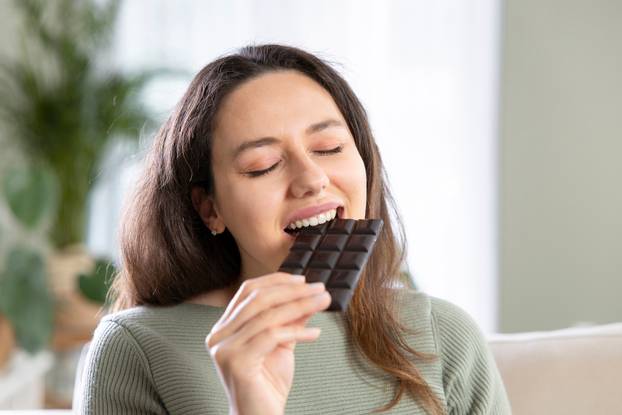 Beautiful young woman biting a chocolate bar