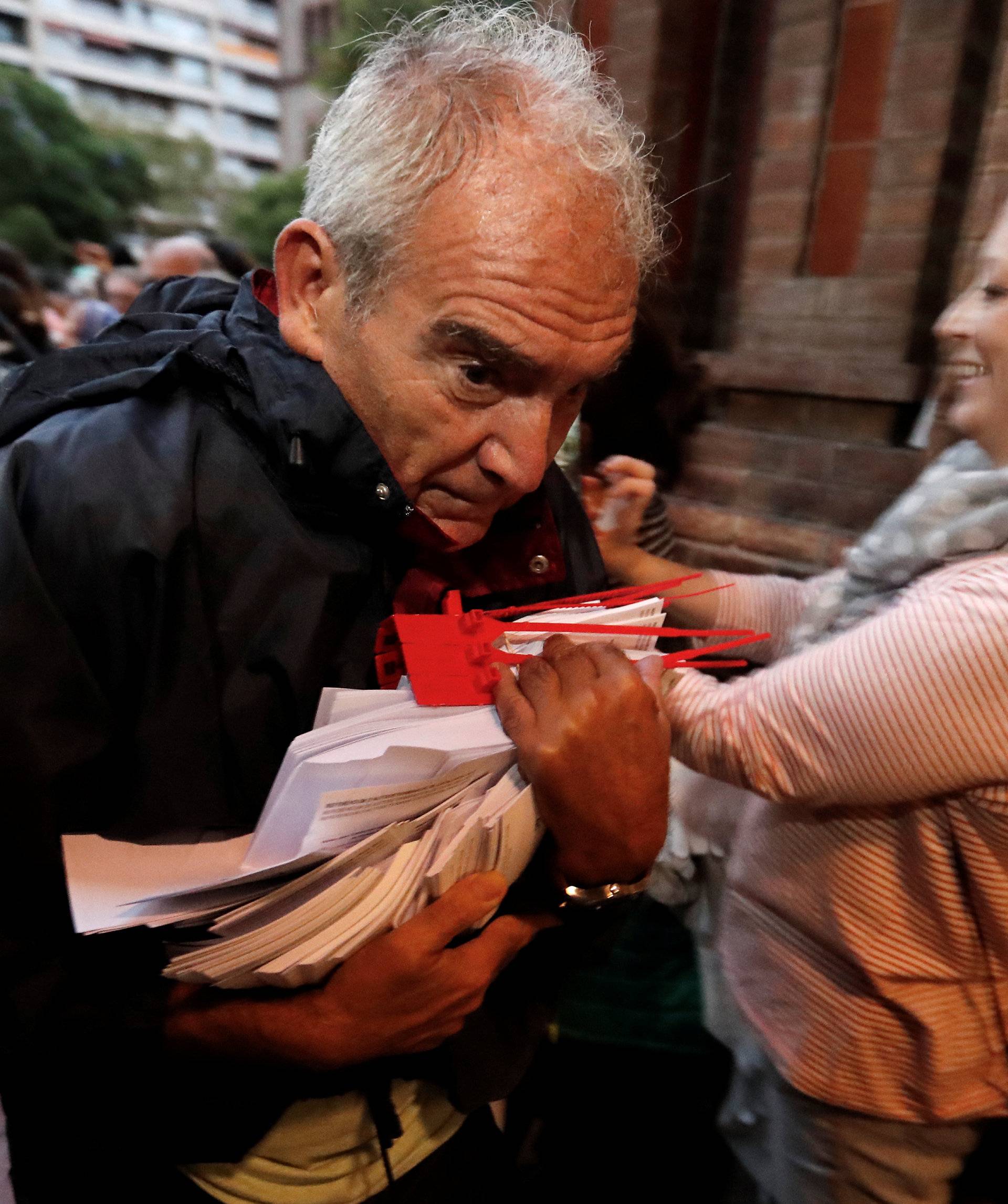 A  man holds ballots at a polling station for the banned independence referendum in Barcelona