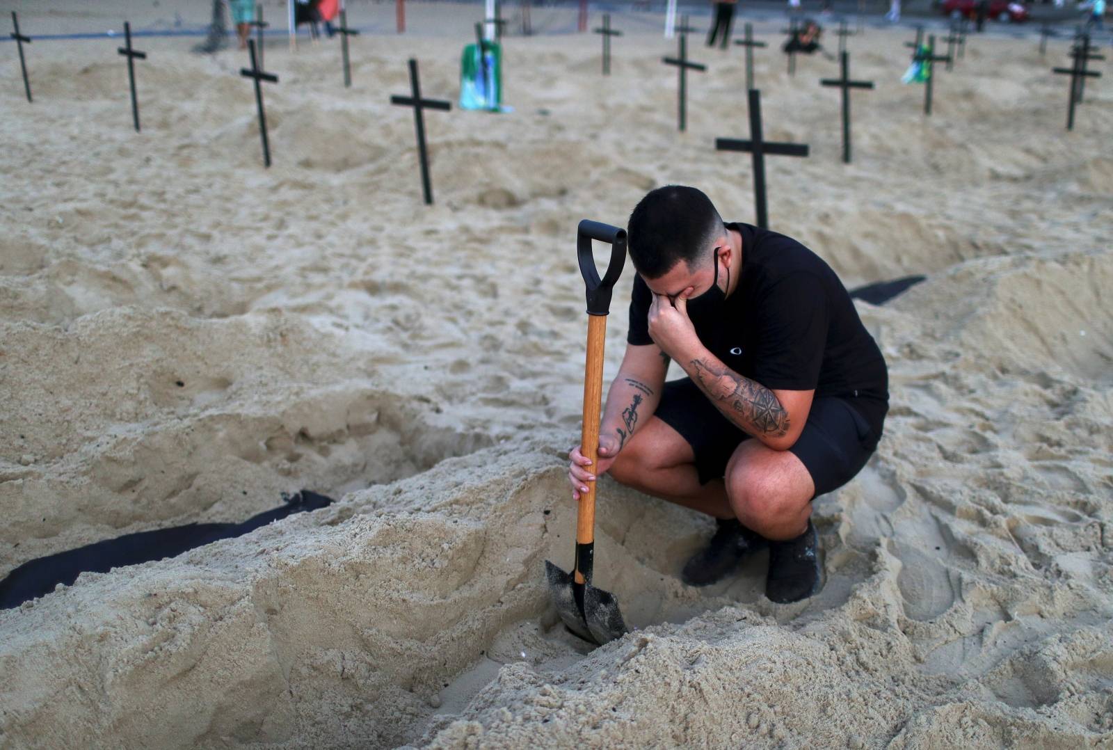 An activist of the NGO Rio de Paz wearing a protective mask reacts as he attends a demonstration during which one hundred graves were dug on Copacabana beach symbolising the dead from the coronavirus disease (COVID-19), in Rio de Janeiro