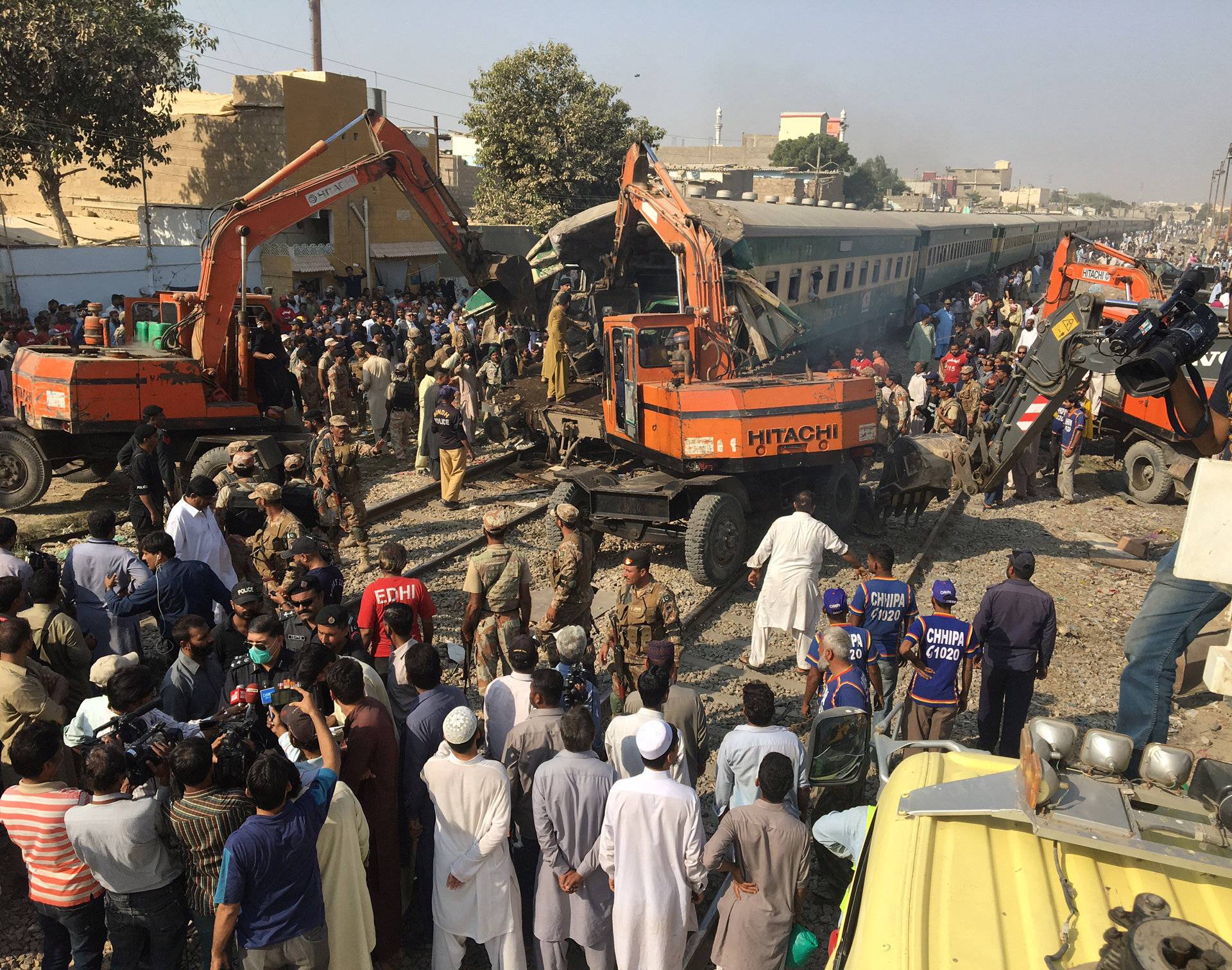 Rescuers workers use heavy machinery on the car of a train which crashed outside Karachi,