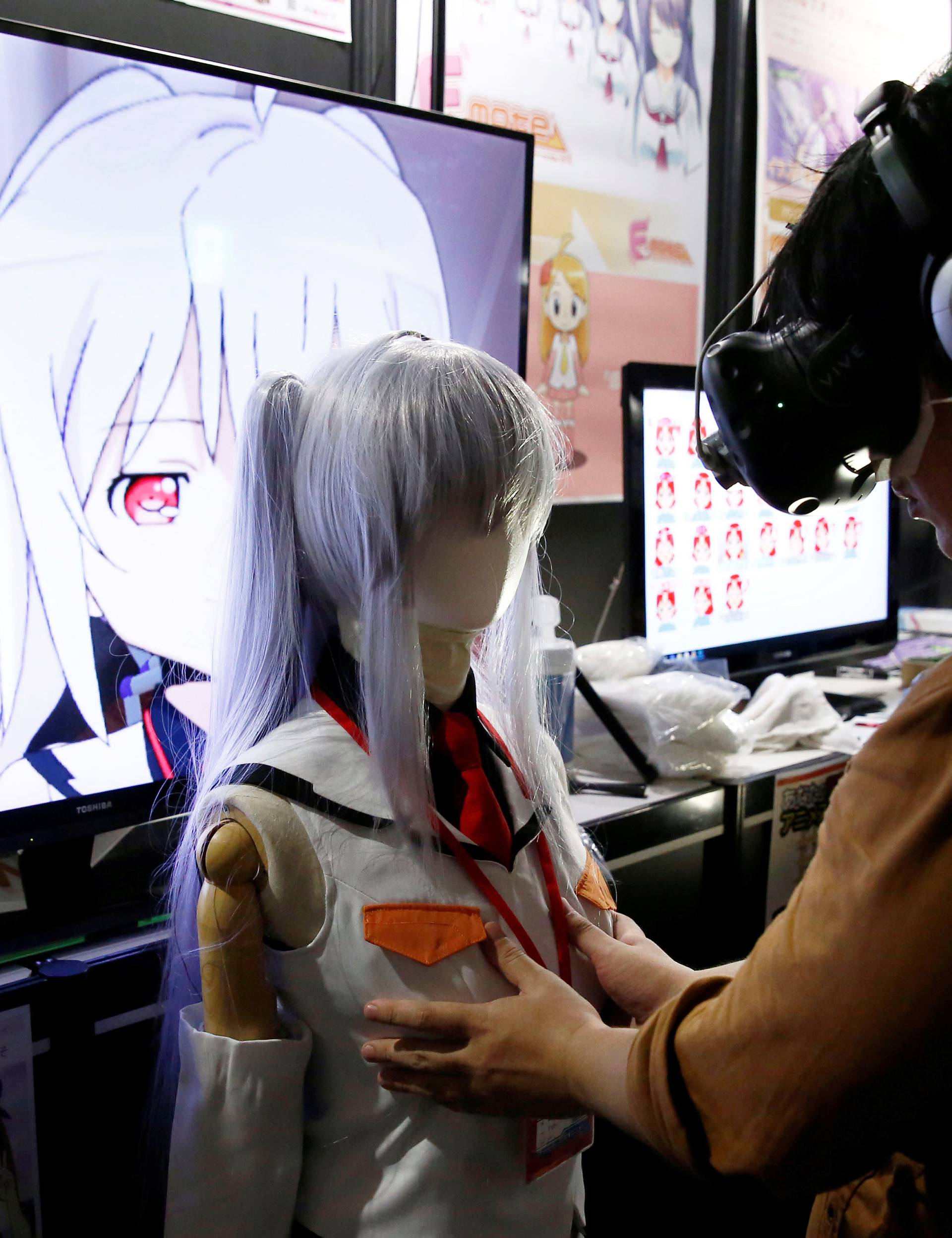 A man touches a mannequin as he tries out a M2 Co.Ltd's "E-mote" system as the monitor shows the image from the VR device at Tokyo Game Show 2016 in Chiba
