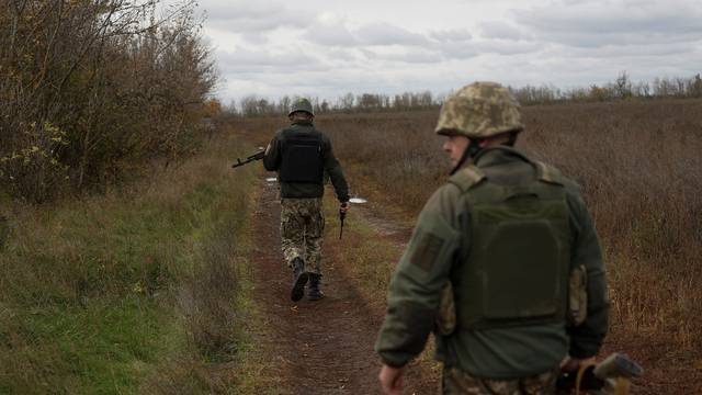 Ukrainian servicemen Ivan and Vitalii walk in a field at a frontline in Mykolaiv region