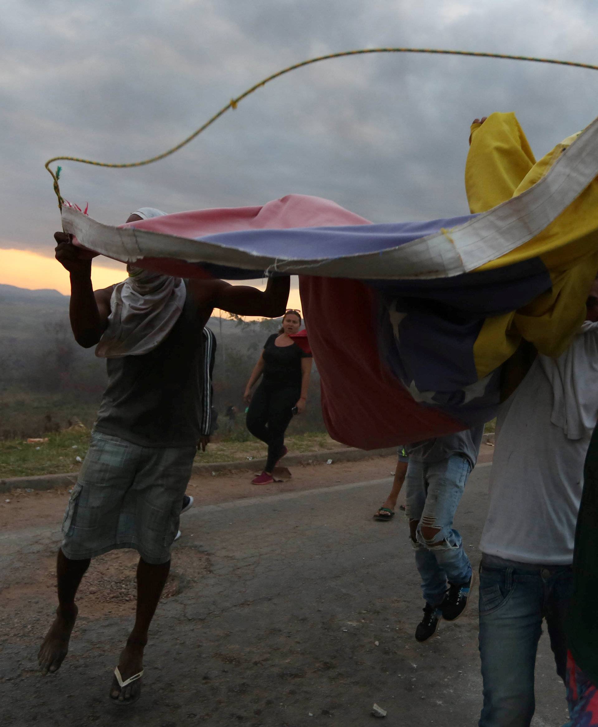 People hold Venezuela's national flag at the border between Venezuela and Brazil in Pacaraima