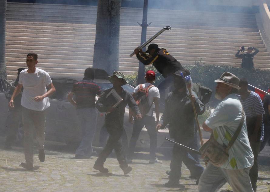 Government supporters break a car outside the National Assembly, in Caracas