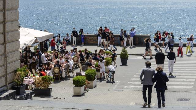 A crowd of people walk wearing protective masks on the seafront in Naples