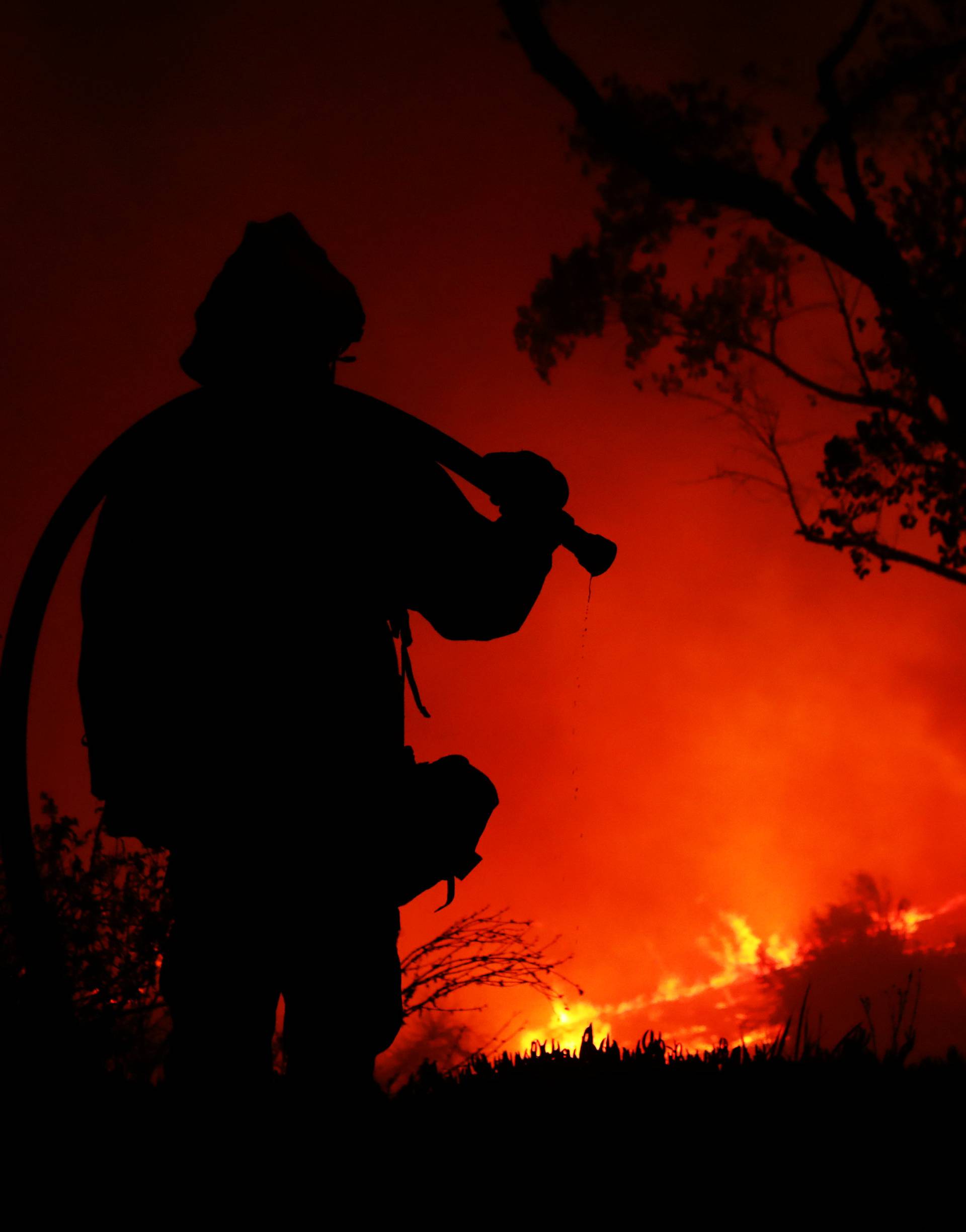 A firefighter working on extinguishing the Lilac Fire a fast moving wildfire is seen in Bonsall