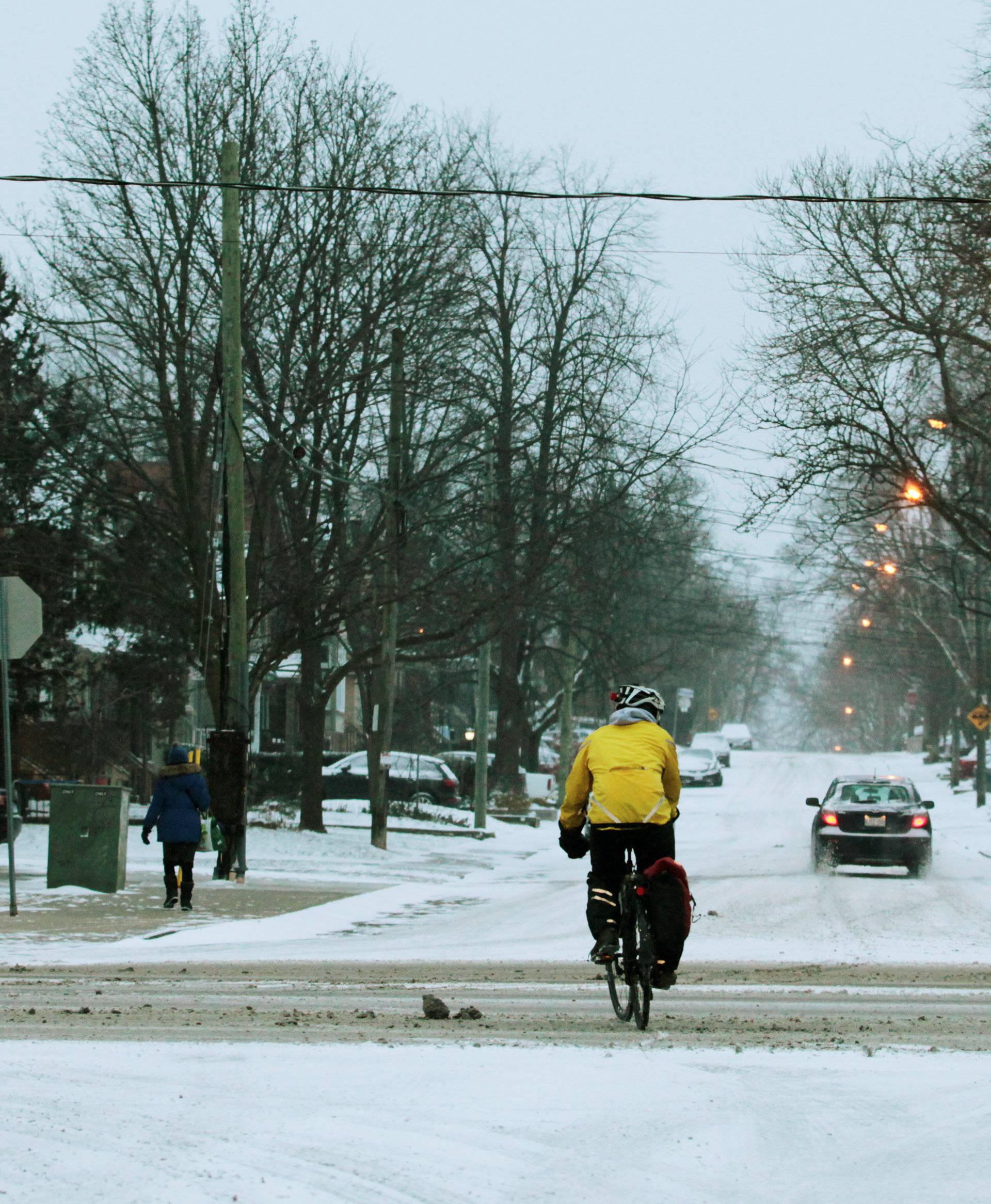 Cyclist navigates traffic after an overnight snow storm, in Toronto