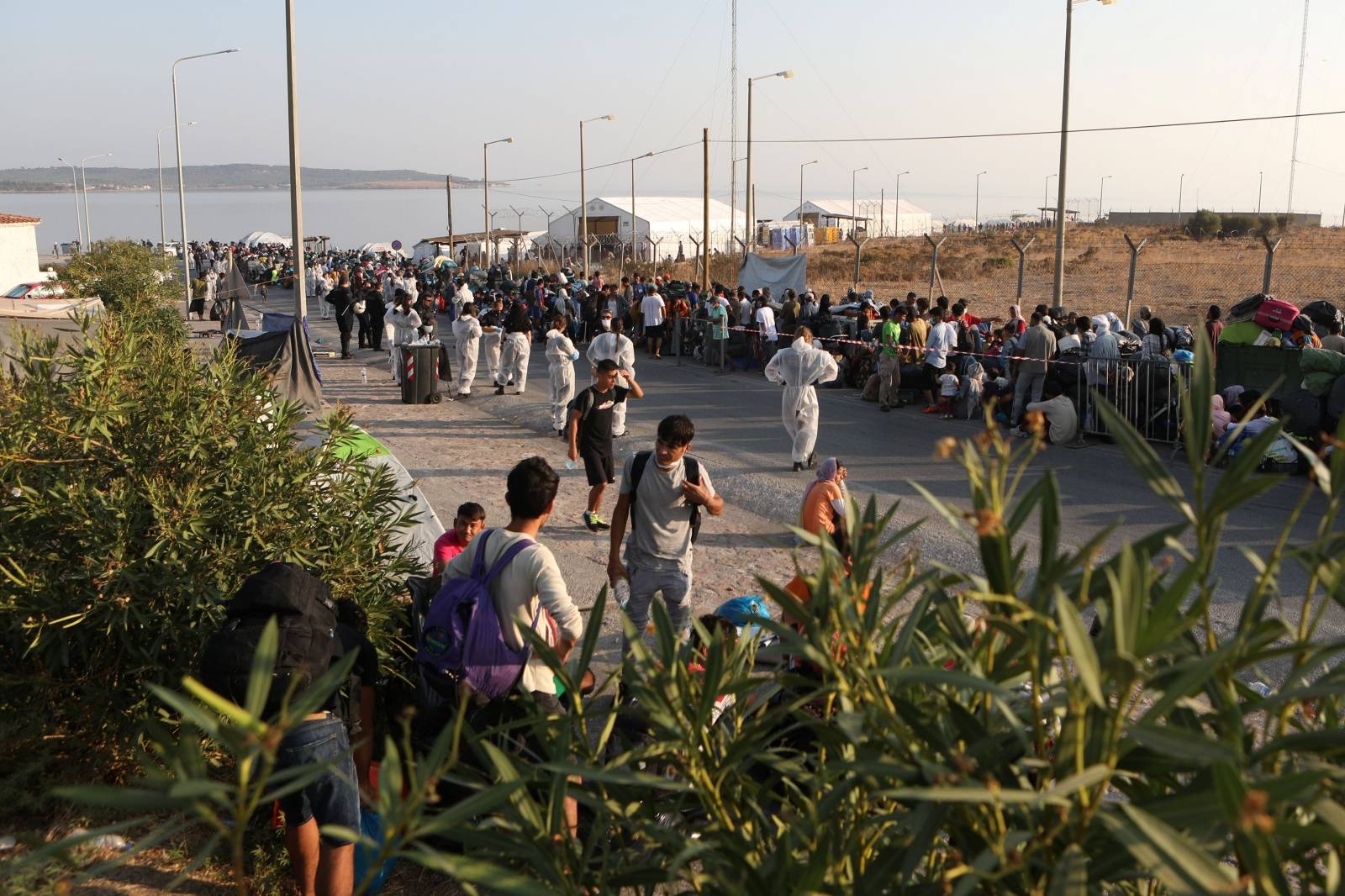 Refugees and migrants, from the destroyed Moria camp, line up to enter a new temporary camp, on the island of Lesbos