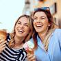 Two young women laughing and holding ice cream in hand