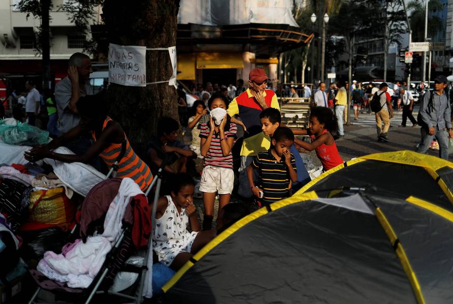 Children from homeless families that were living in the building that caught on fire, have lunch donated by well-wishers, next to a church at Largo do Painsandu Square in Sao Paulo
