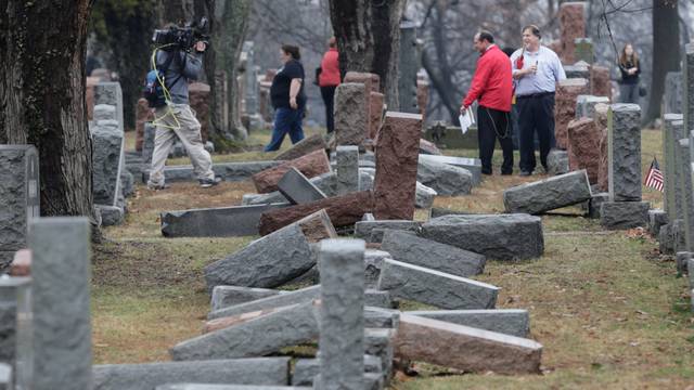 People view toppled Jewish headstones after a weekend vandalism attack on Chesed Shel Emeth Cemetery in University City