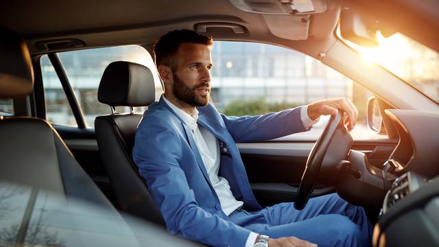 Attractive man in business suit driving car