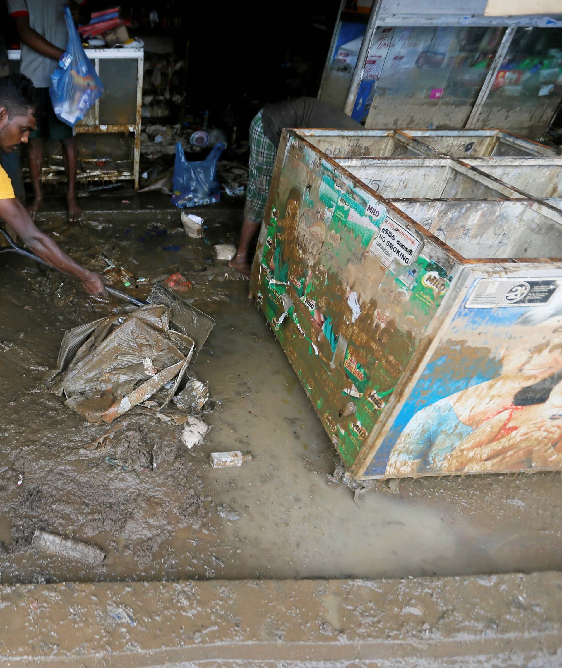 A man cleans his shop which was affected by the floods in Biyagama