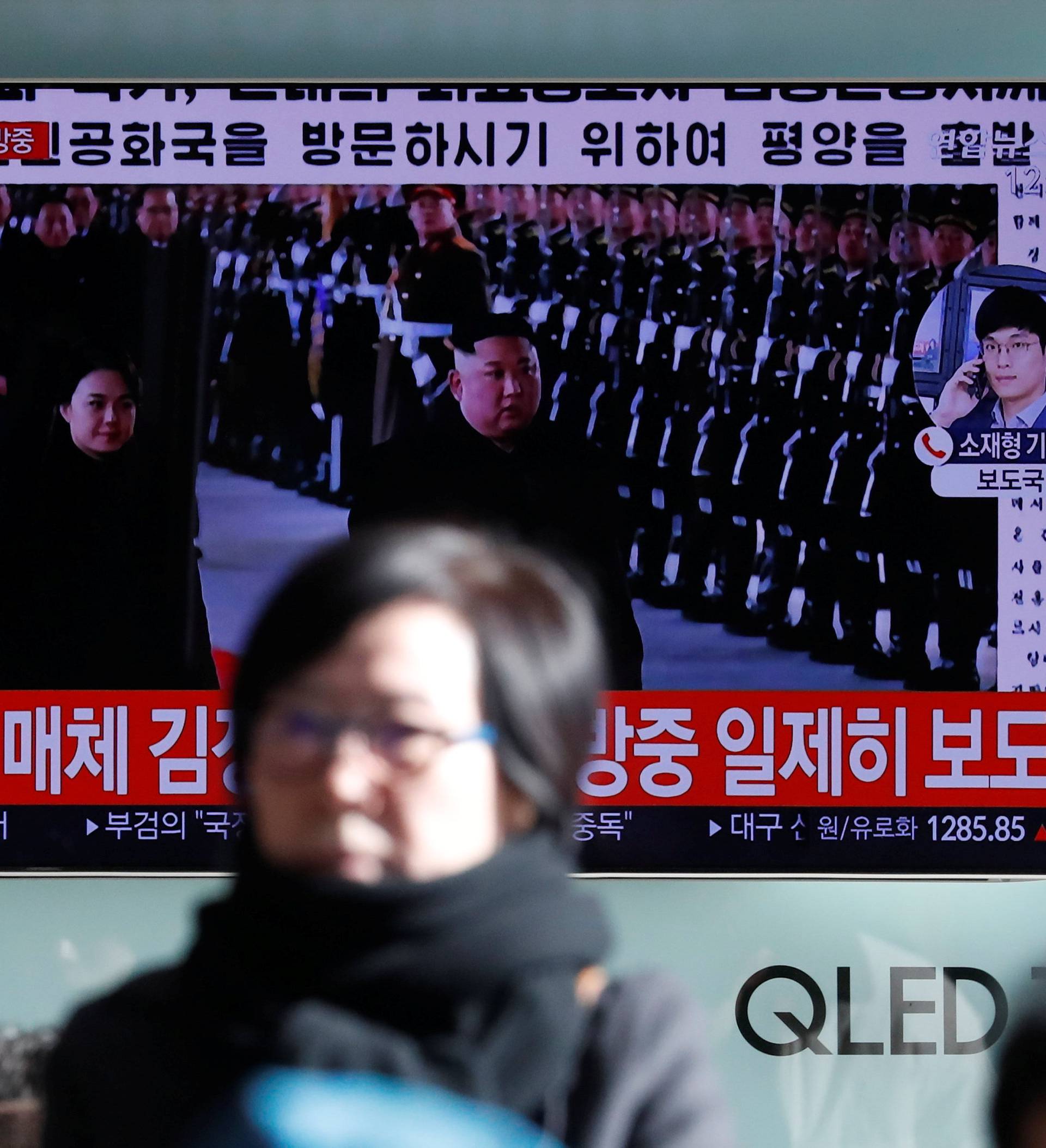People watch a TV broadcasting a news report on North Korean leader Kim Jong Un's visit to China, in Seoul