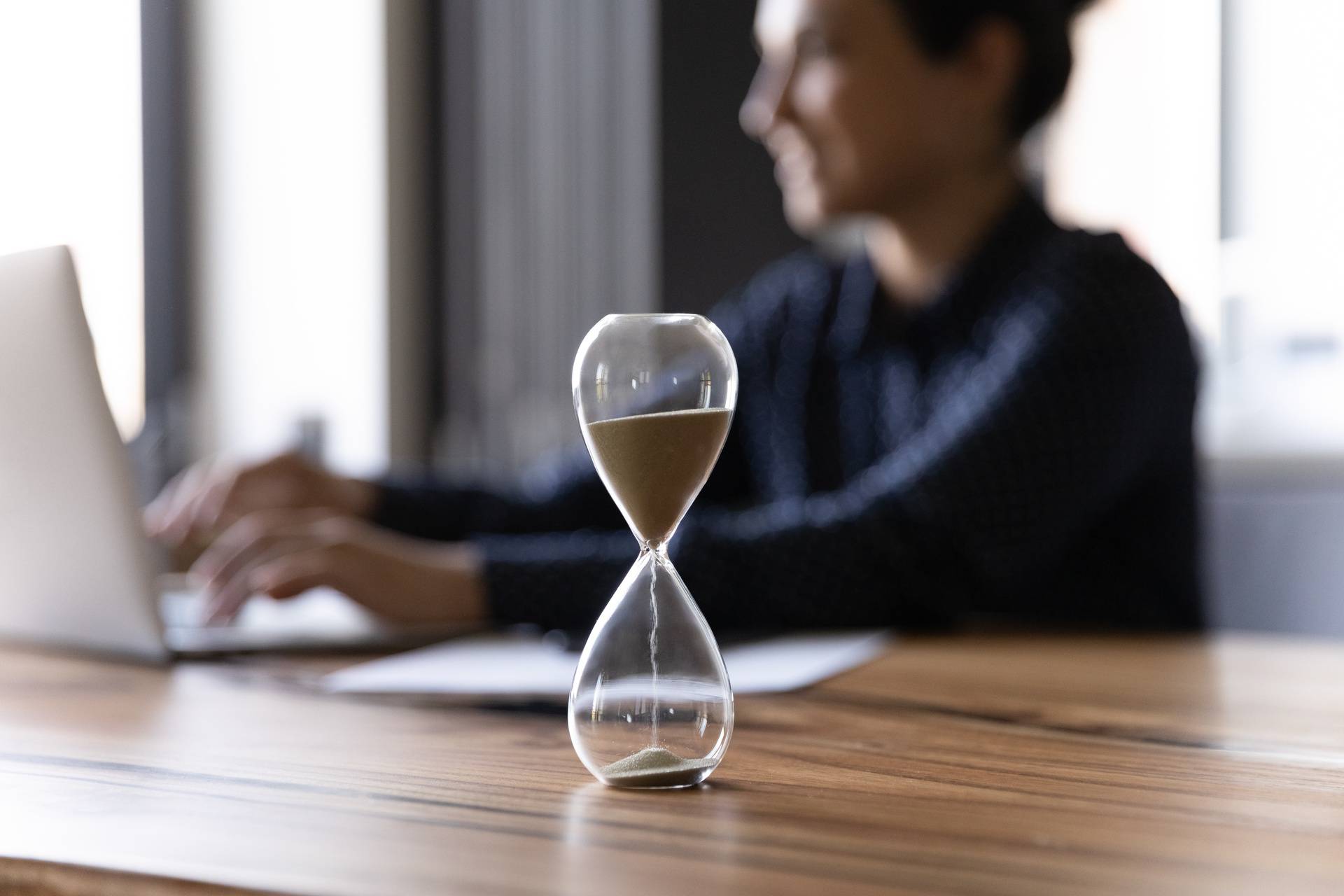 Close,Up,Hourglass,Measuring,Time,,Standing,On,Wooden,Office,Table,