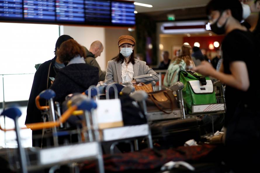 Travellers wearing masks arrive on a direct flight from China, in Paris