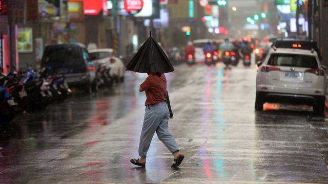 Person braves strong winds while crossing a street in Taipei