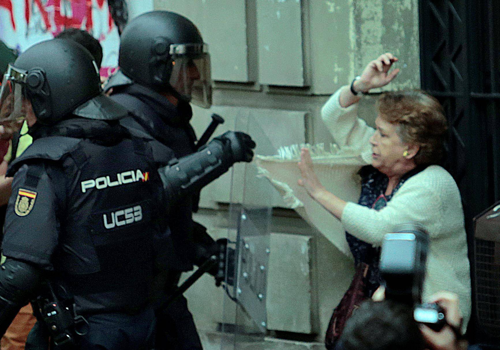 A woman is grabbed by riot police near a polling station for the banned independence referendum in Barcelona