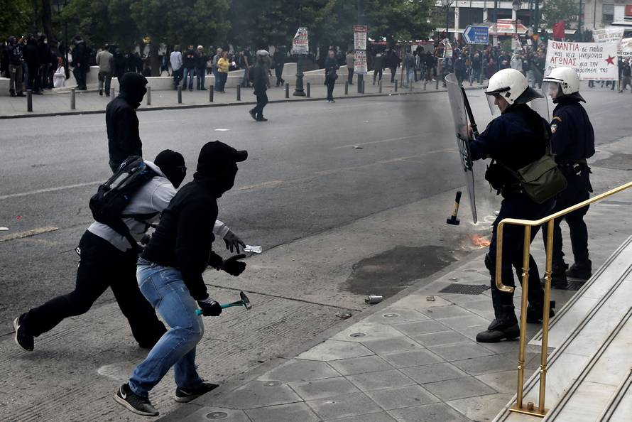 A demonstrator throws a hammer at riot police during a demonstration marking a 24-hour general strike against the latest round of austerity in Athens