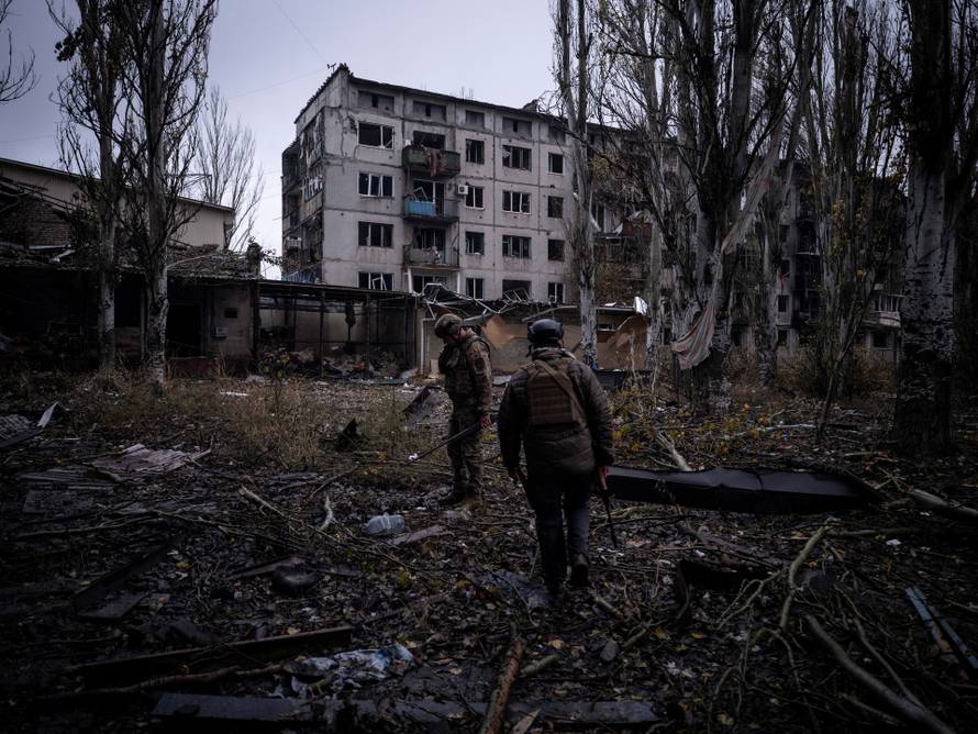 Ukrainian servicemen inspect an area next to apartment buildings damaged by Russian military strikes in the frontline town of Kostiantynivka