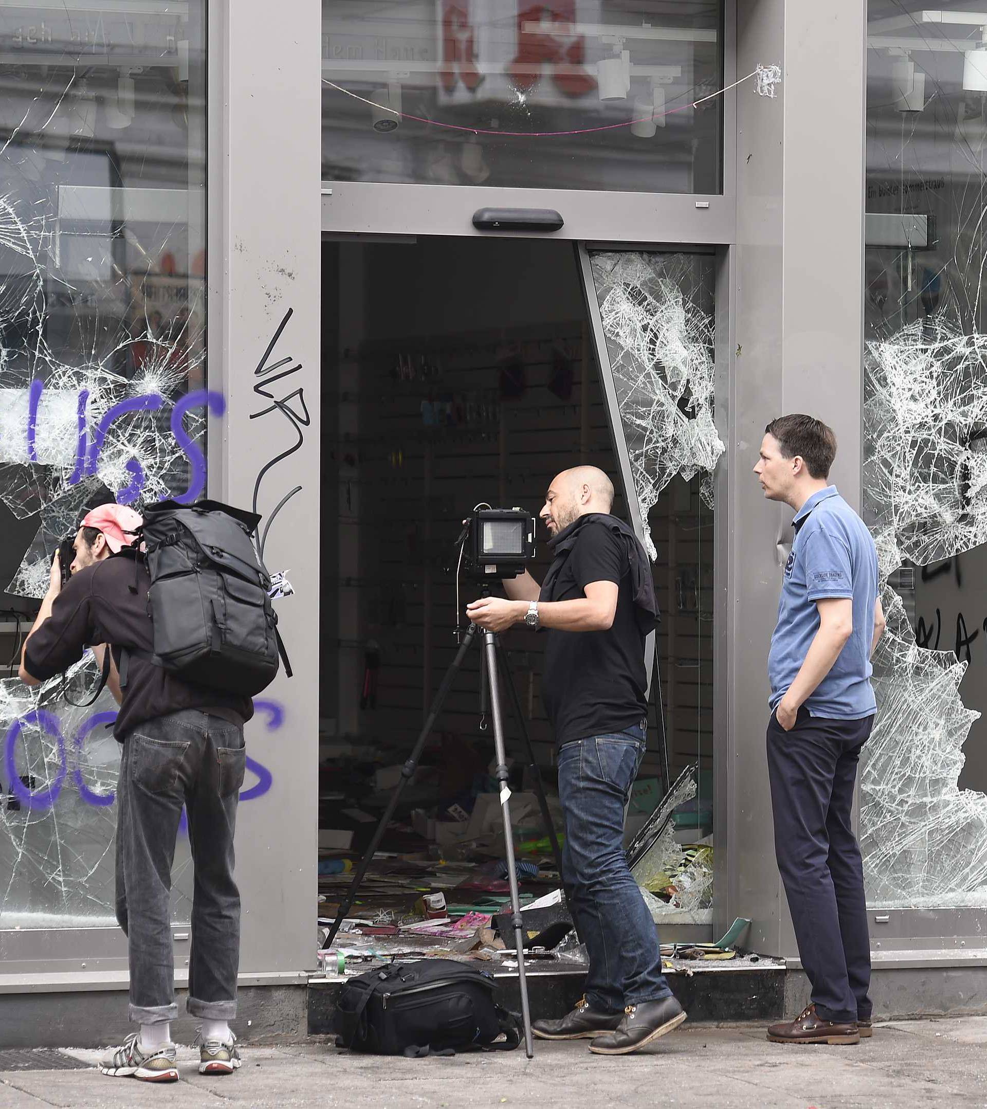People take pictures of a store, damaged after demonstrations at the G20 summit in Hamburg