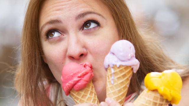 young woman licking on three ice cream cones