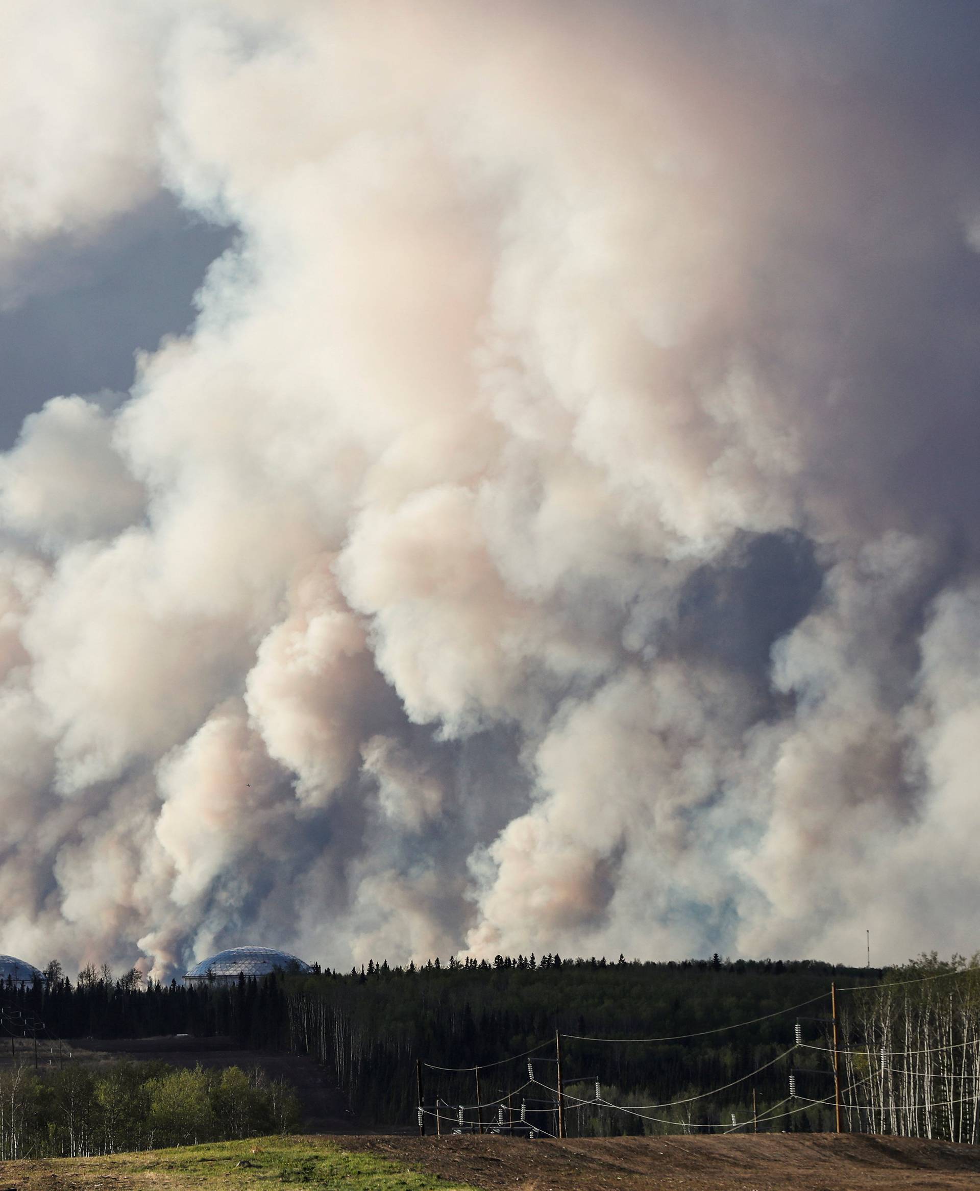 Smoke billows behind a structure from the Fort McMurray wildfires in Kinosis