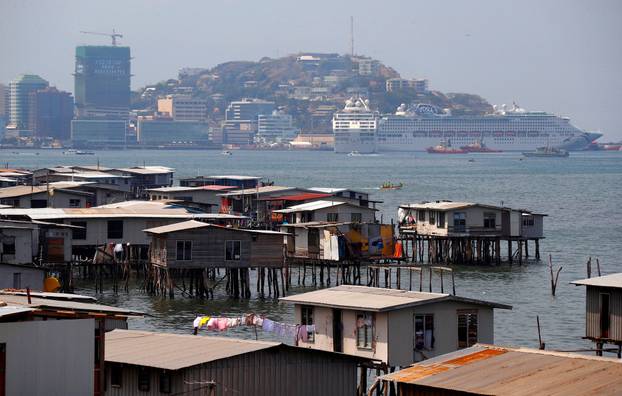 FILE PHOTO: A large cruise ship is docked opposite the stilt house village called Hanuabada, located in Port Moresby Harbour in Papua New Guinea