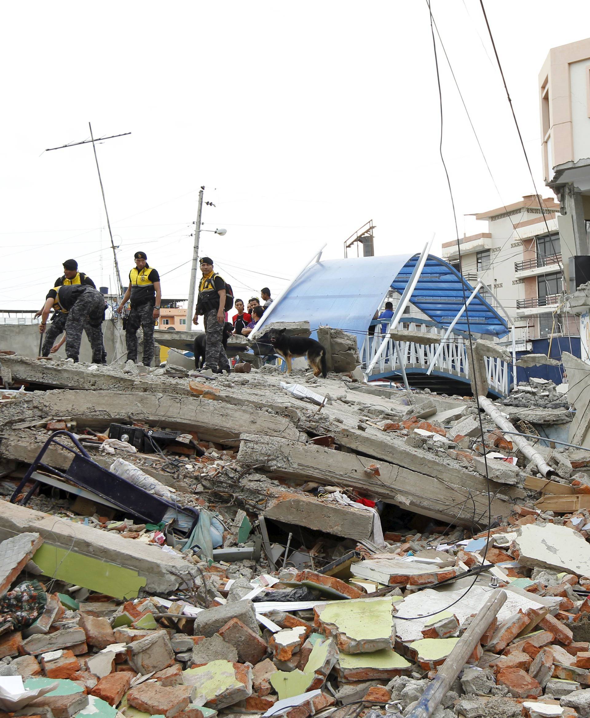 Police officers stand on debris after an earthquake struck off Ecuador's Pacific coast, at Tarqui neighborhood in Manta