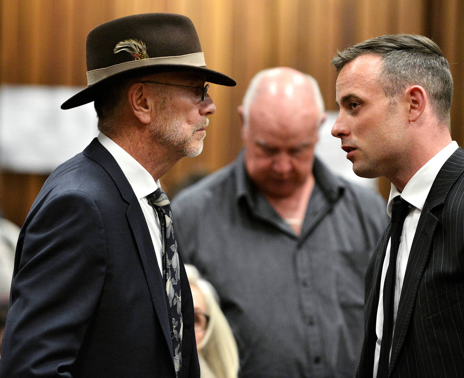 Former Paralympian Oscar Pistorius speaks with his uncle Arnold Pistorius at his sentencing for the murder of Reeva Steenkamp at the Pretoria High Court