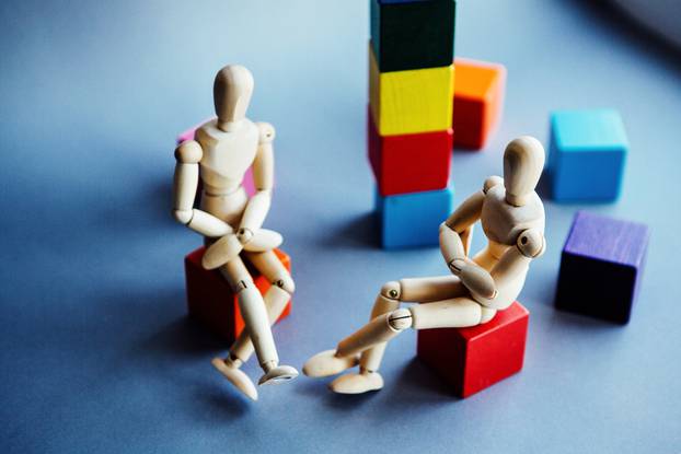 The,Figurine,Of,A,Wooden,Man,Sitting,Opposite,Each,Other