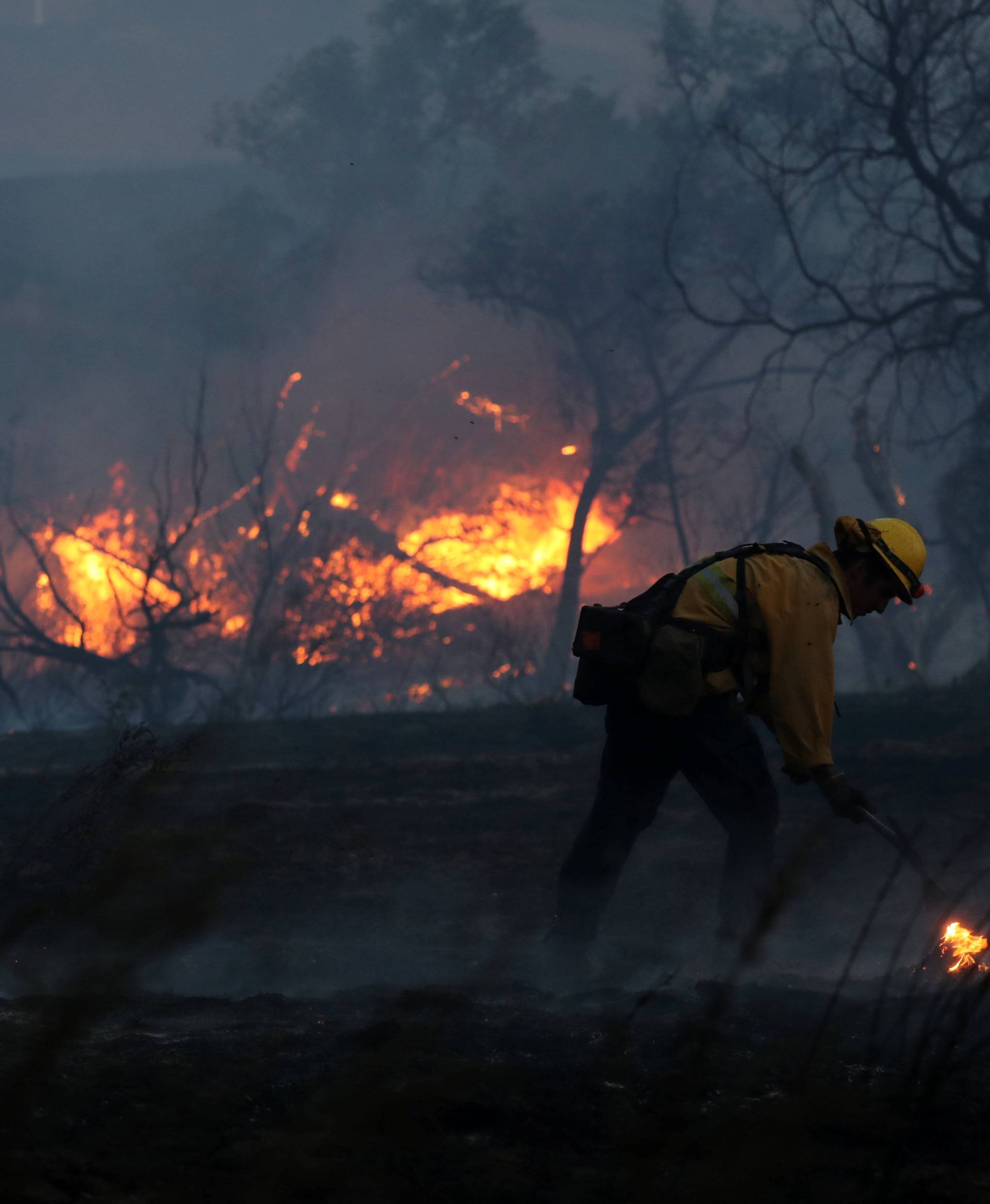 Firefighters work to put out hot spots on a fast moving wind driven wildfire in Orange, California