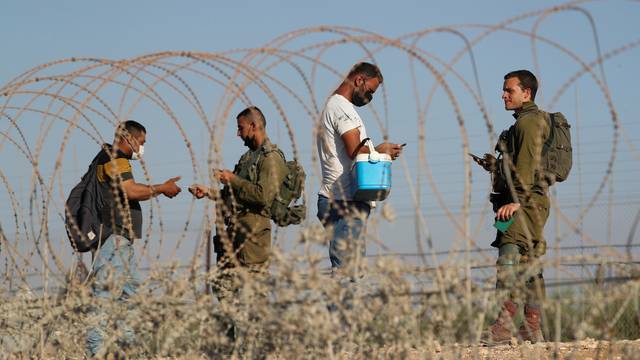 Israeli soldiers check documents of Palestinians as they cross back to the West Bank from Israel by the village of Muqeibila