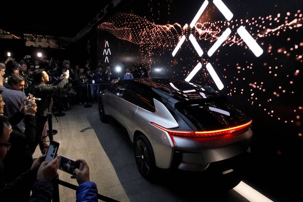 Journalists gather around a Faraday Future FF 91 electric car during an unveiling event at CES in Las Vegas