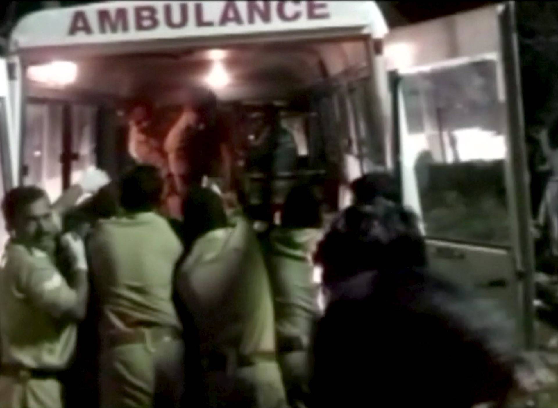 Police rush injured into an ambulance after a fire broke out as people gathered for a fireworks display at a temple in Kollam, southern India