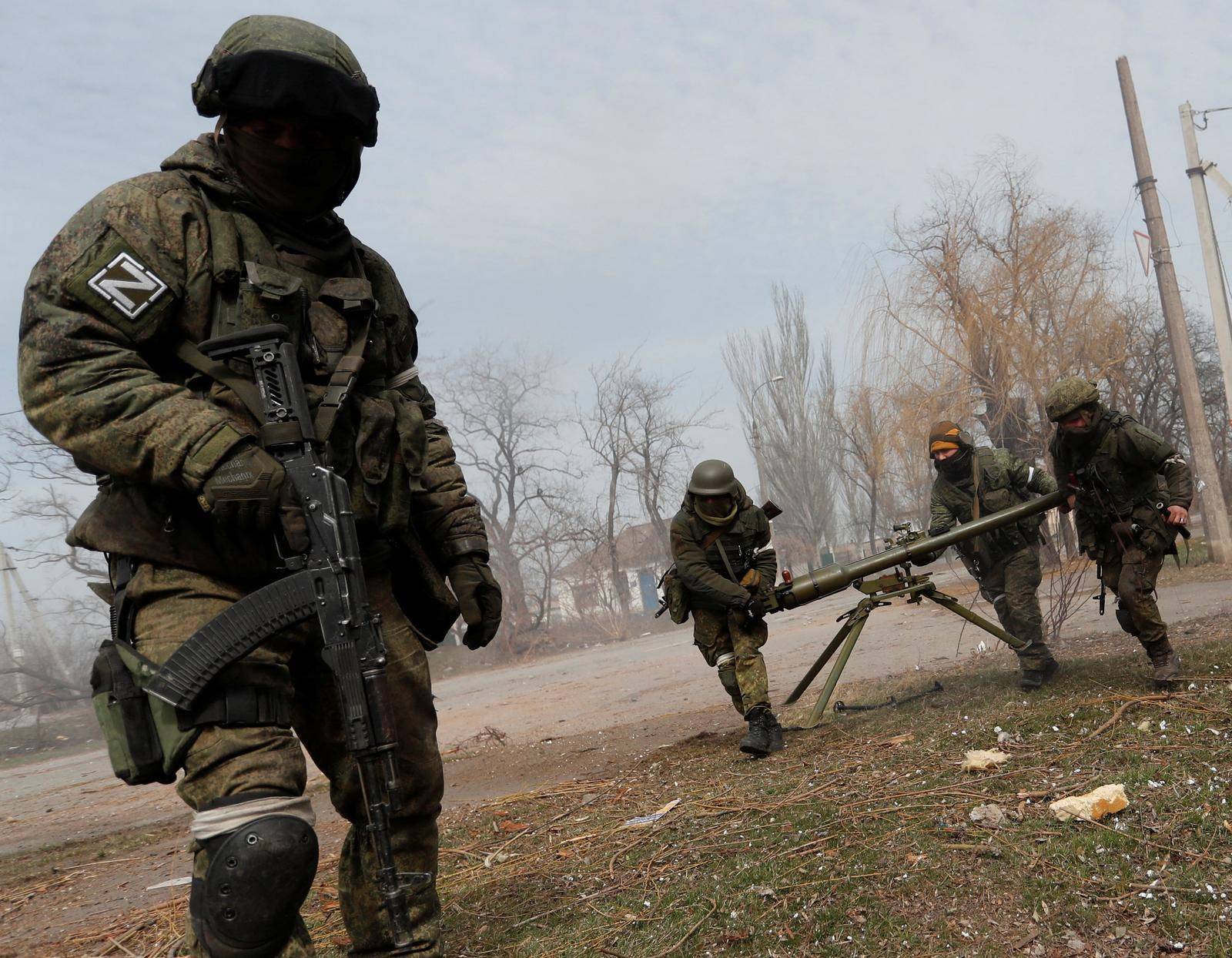 Service members of pro-Russian troops fire an anti-tank grenade launcher in Mariupol