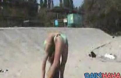 Djevojka na plaži savija tijelo kao da je od gume