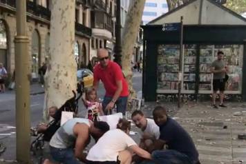 People help an injured woman after a van crashed into pedestrians near the Las Ramblas avenue in central Barcelona