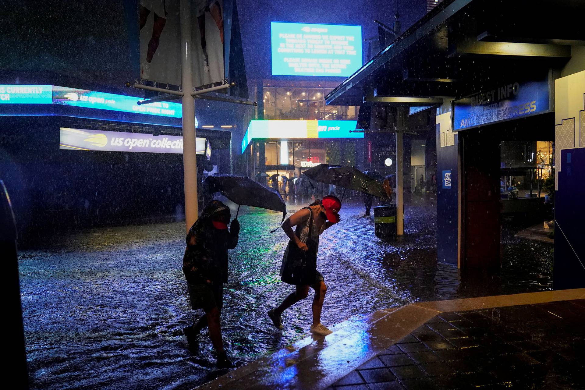 Spectators walk through flooded paths near Louis Armstrong Stadium