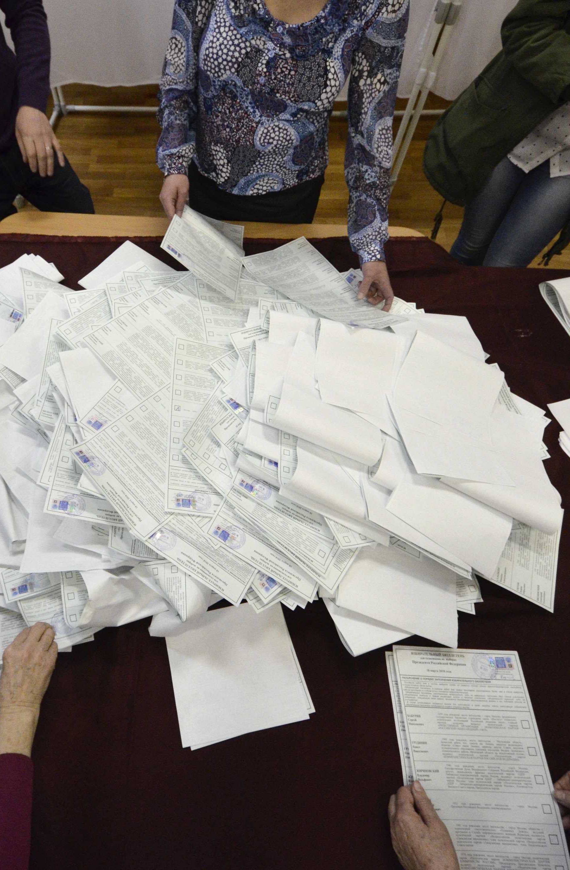 Members of a local election commission sort ballots before starting to count votes during the presidential election in Vladivostok