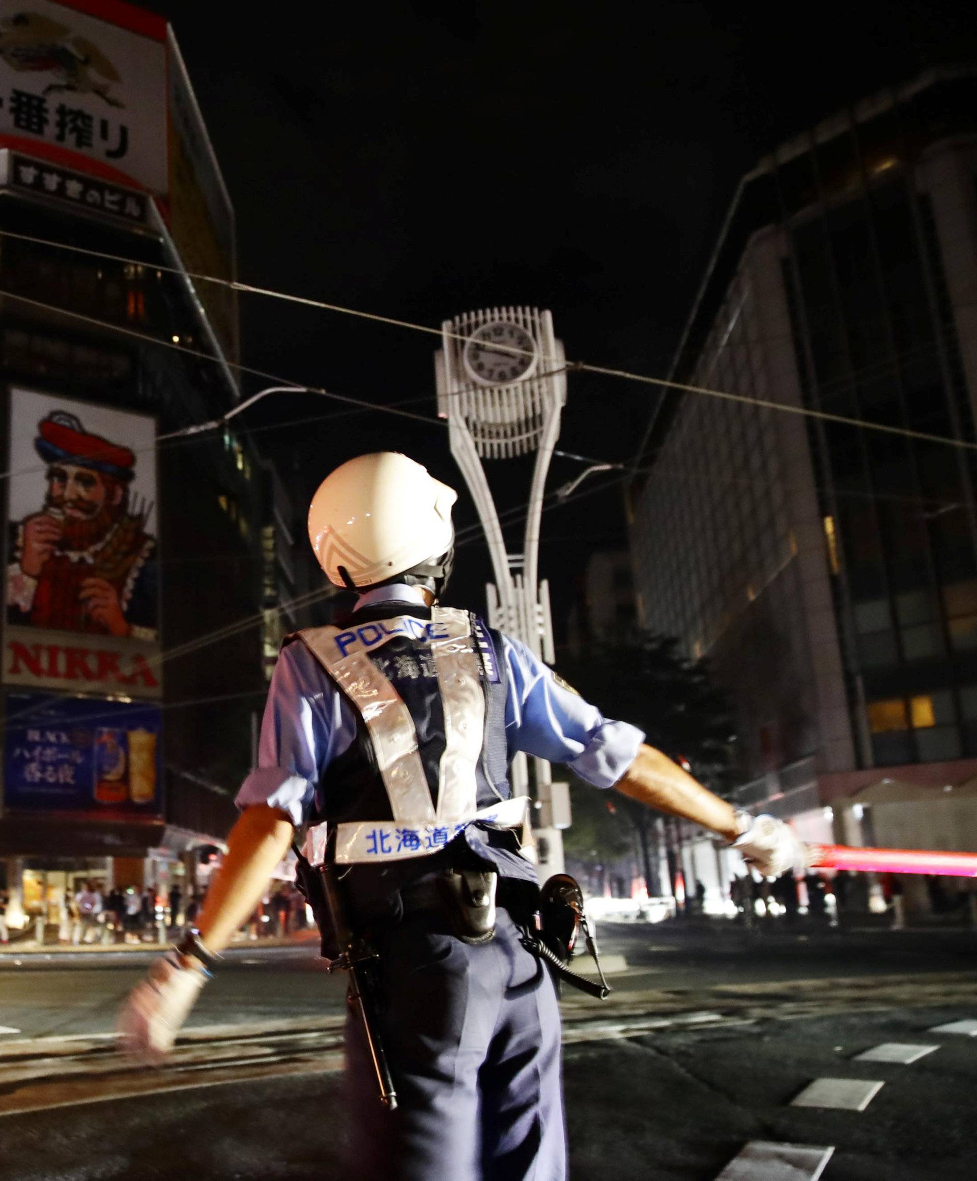 A police officer is seen during blackout after a powerful earthquake hit the area at a cross-point in Sapporo
