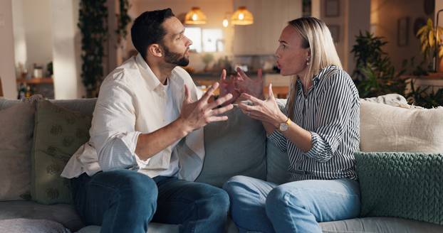 Home, sofa and couple with conflict in marriage, toxic relationship and disagreement for divorce. Night, man and sad woman with fight for separation, breakup and communication problem in living room