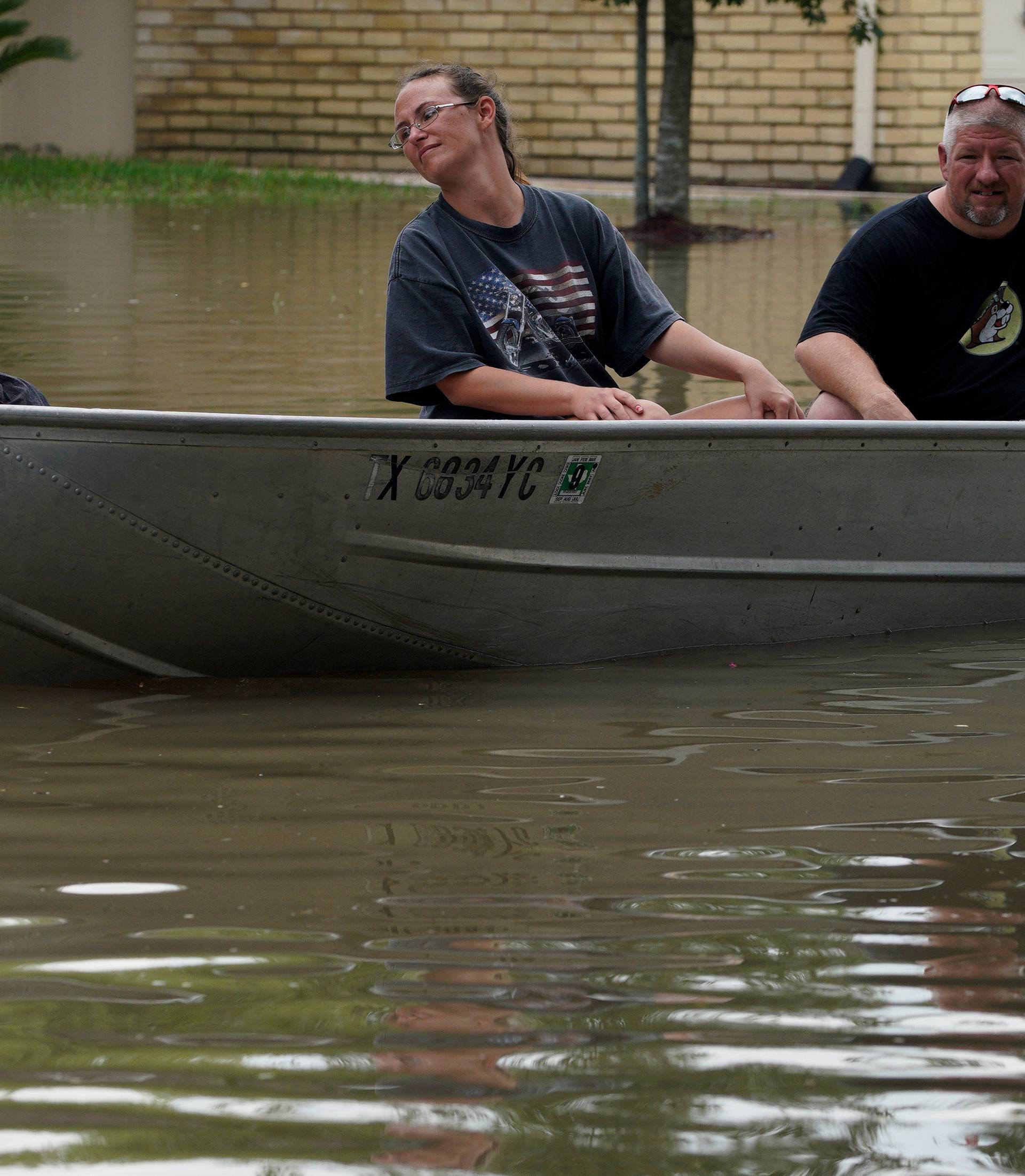 Kyle Iselt touches the water as mother Melissa Buchanan and father Shannon Iselt drive a boat through the  Tropical Storm Harvey floodwaters in north western Houston